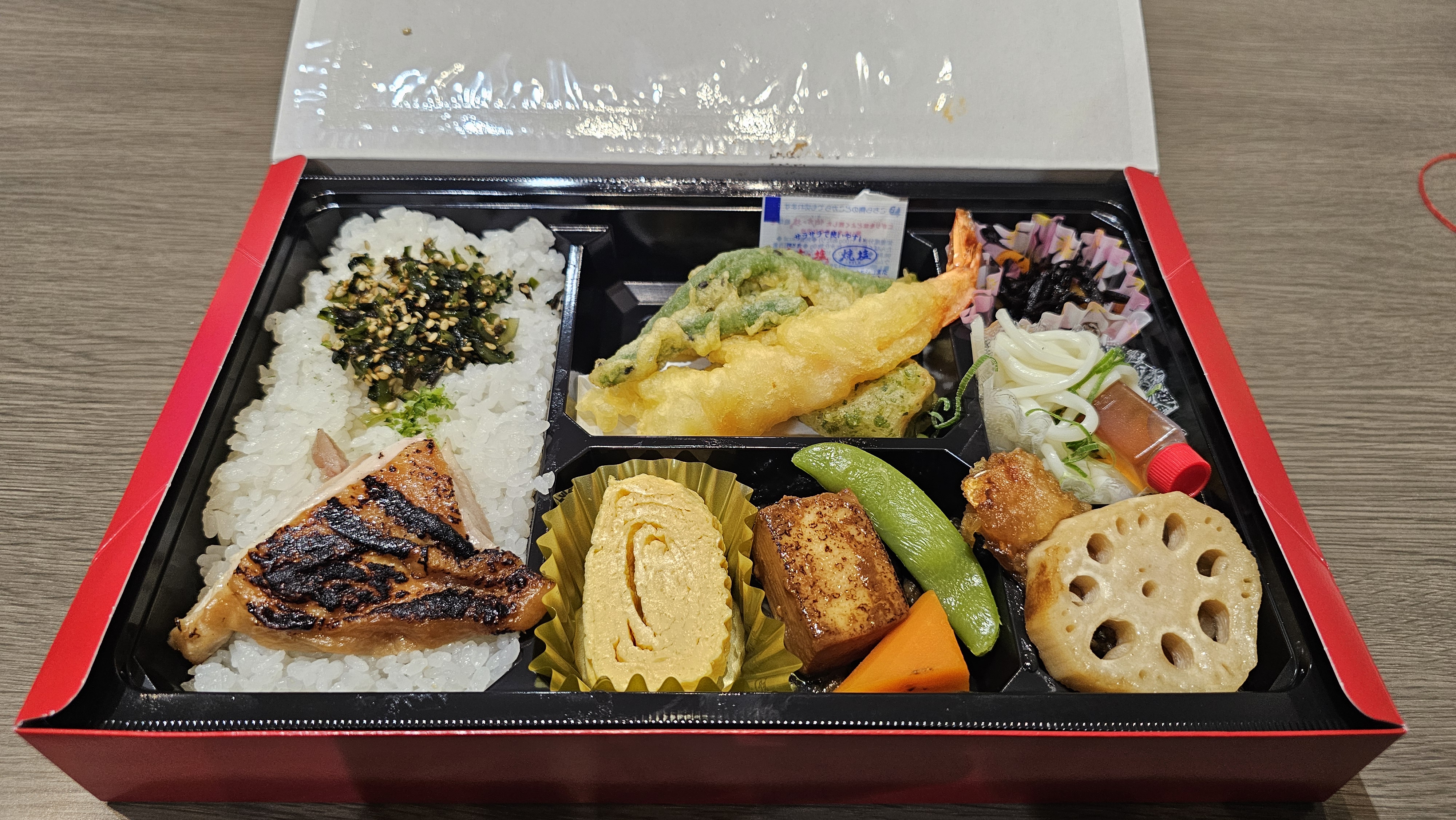 A bento lunch with rice, grilled fish, tempura, and vegetables